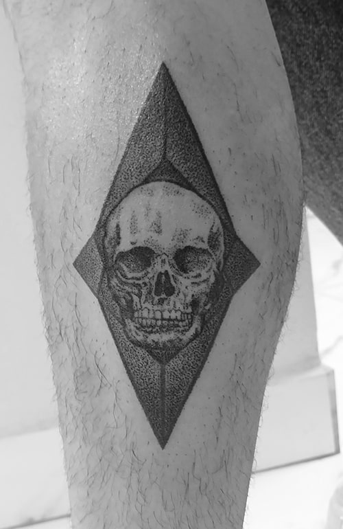 Tatuagem de crânio com figura geométrica ao fundo